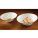 Two RAK Porcelain ivory extra deep bowls filled with food on a wooden table.