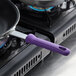 A purple Vollrath pan handle sleeve on a frying pan on a stove.