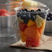 A Solo clear plastic squat cup filled with fruit.