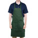 A man wearing a Chef Revival hunter green apron with 1 pocket standing in a professional kitchen.
