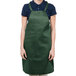 A woman wearing a Chef Revival hunter green bib apron with one pocket.