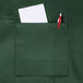 A Chef Revival hunter green apron with a pocket holding a pen and paper.