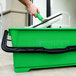 A hand holding a squeegee in a green Unger ProBucket.