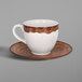 A white and brown porcelain coffee cup and saucer with a brown liquid in the cup on a table.