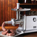 A Weston electric meat grinder with sausage on it.