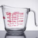 A clear glass Anchor Hocking measuring cup with red writing on it.