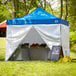 A Backyard Pro Courtyard Series tent with a blue and white canopy set up on grass.