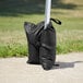 A black bag with a strap on a white post.