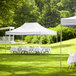 A white Backyard Pro canopy set up in a grassy area with tables and chairs.