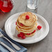 A stack of pancakes with raspberries on top on a white Acopa stoneware plate.