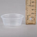 A clear plastic Dart portion cup next to a ruler.