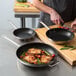 A chef cooking meat and vegetables in a Vigor SS1 Series stainless steel frying pan.