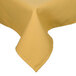 A yellow Intedge poly/cotton blend tablecloth with a hemmed edge on a table.
