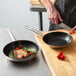 The Vigor SS1 frying pan with meat and vegetables in it on a wood surface.