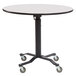 A black and white National Public Seating Cafe Time II round mobile table with wheels on it.