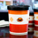 A close up of a red and white Choice paper cup with a vented paper lid.