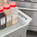 A Continental gray utility cart with containers of spices with red caps.