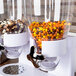 A white Zevro double dry food dispenser on a counter filled with candy and nuts.