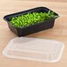 A Pactiv Newspring black plastic rectangular microwavable container with peas inside.