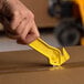 A hand holding a yellow Pacific Handy Cutter tool cutting a box.