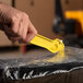 A hand holding a yellow Pacific Handy Cutter to cut plastic.