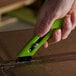 A person using a Pacific Handy Cutter green right-handed safety cutter to cut a box.