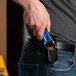 A man wearing jeans and holding a Pacific Handy Cutter black S7 cutter holster in his back pocket.