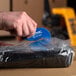 A person using a Pacific Handy Cutter blue bag cutter to open a plastic bag.