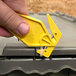 A hand holding a yellow Pacific Handy Cutter to open a box.