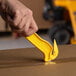 A person using a Pacific Handy Cutter yellow food safe cutter with a sharp blade to cut a box.