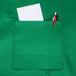 A Chef Revival Kelly Green bib apron with a pocket holding a pen and paper.