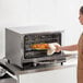 A woman in an apron putting food into a Galaxy countertop convection oven.