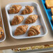 A white Cambro market tray of pastries on a bakery display counter.