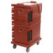 A brick red plastic Cambro container with a black handle on wheels.