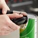 A hand using the OXO Good Grips can opener to open a can.