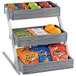 A Cal-Mil 3-tier vertical merchandiser with fruit, chips, and snacks.