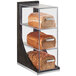 A Cal-Mil oak wood three tier bread case with different types of bread displayed.