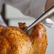 A person using a Fox Run stainless steel turkey baster to a roasted turkey.