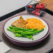 A Dinex cranberry induction base with a plate of food, rice, green beans, and berries.