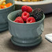 A close-up of a Dinex Turnbury insulated bowl filled with raspberries and blackberries on a table.