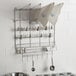 A stainless steel Ateco pastry bag drying rack on a wall with kitchen utensils.