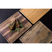 An Elite Global Solutions faux hickory wood melamine serving board with food on it.