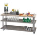 A Cal-Mil Ashwood Gray Oak service cart with shelves holding drinks and food.