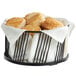 A black wire basket filled with biscuits on a table in a breakfast diner.