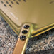A close up of a GI Metal gold anodized aluminum square perforated pizza peel.