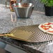 A pizza on a GI Metal square perforated pizza peel over a counter.