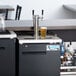 An Avantco black rectangular double tap kegerator with a glass of beer.