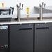 An Avantco black beer dispenser with two taps on a counter.
