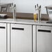 An Avantco stainless steel beer dispenser with two taps on a counter.