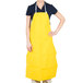 A woman wearing a yellow San Jamar Neo-Flex dishwasher apron.